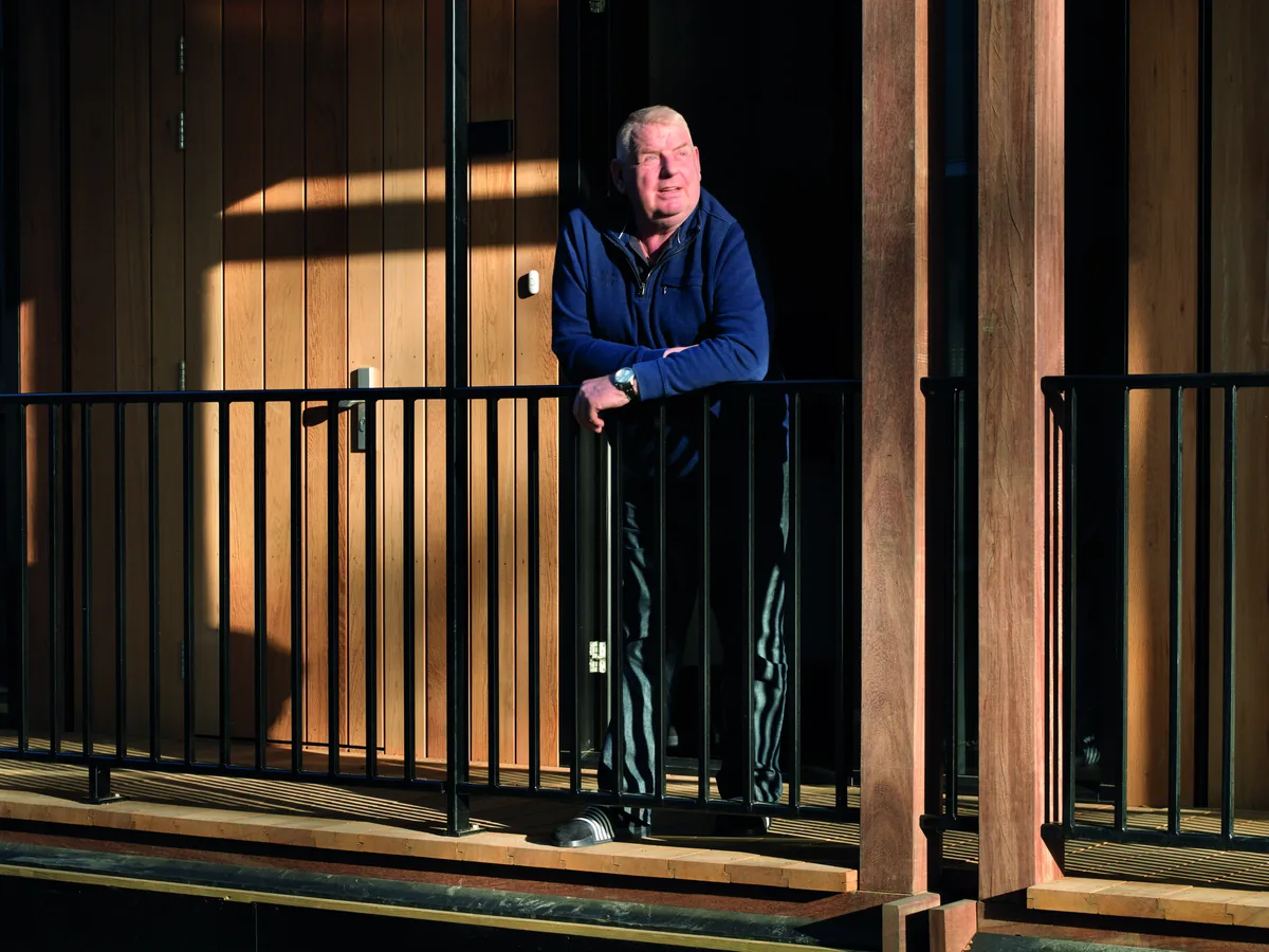 A resident on the balcony of a residential building constructed using Finch Buildings' modular wood construction method